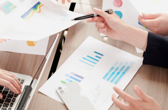 会議や打ち合わせでグラフや資料を囲んで議論するビジネスパーソン